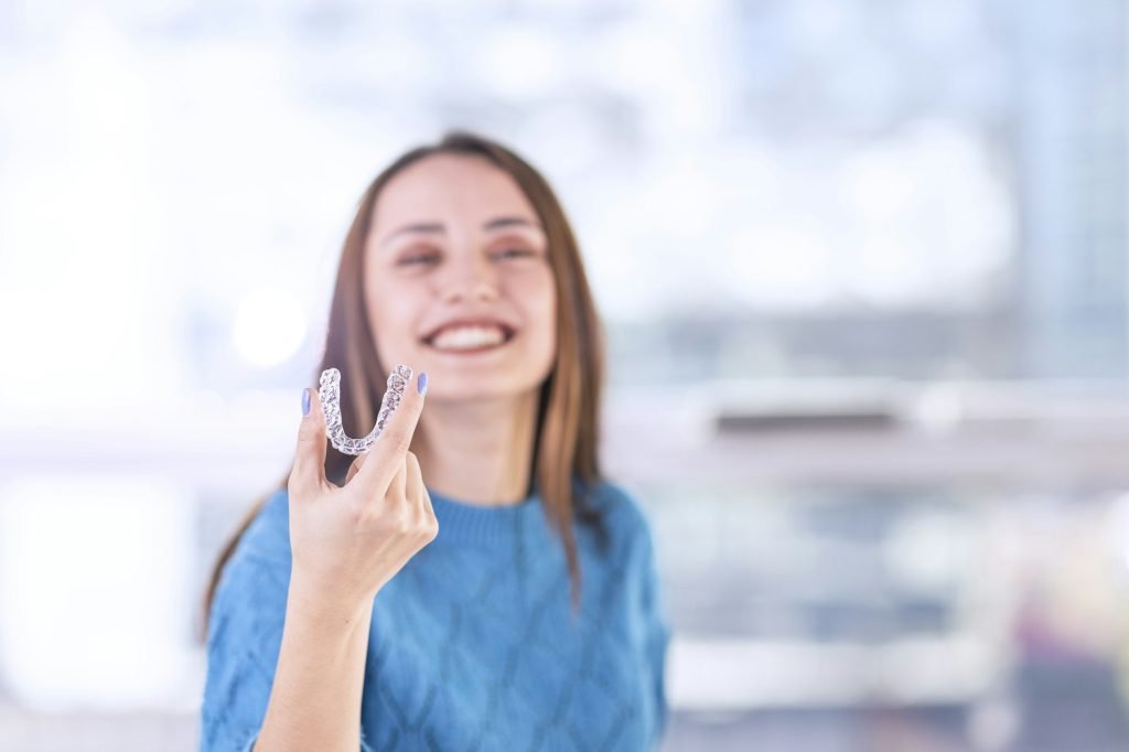 Beautiful smiling Turkish woman is holding an invisalign bracer, includes copy space